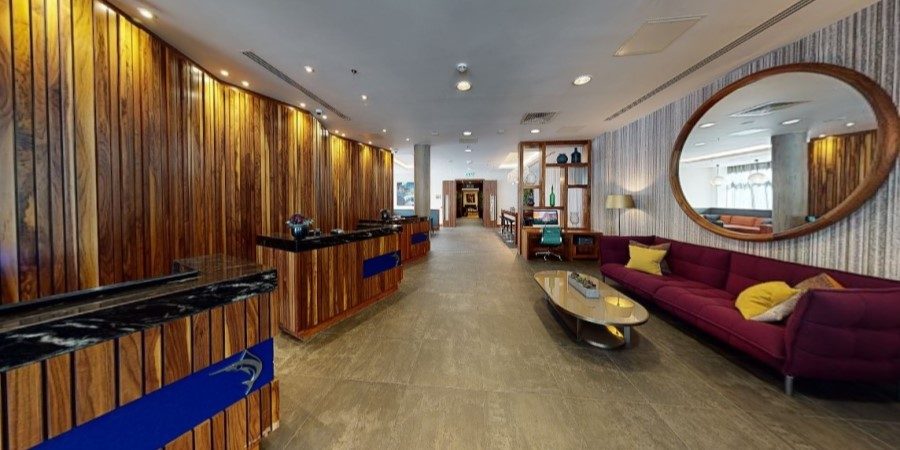 Hotel lobby featuring wooden walls and a large mirror reflecting the elegant interior design.